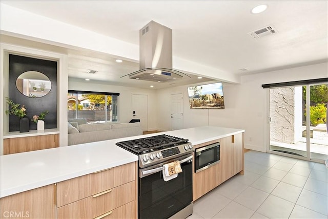 kitchen with island exhaust hood, appliances with stainless steel finishes, plenty of natural light, and light brown cabinets