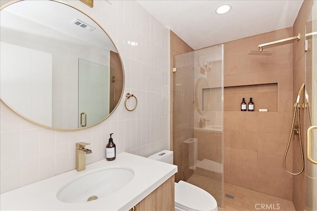 bathroom with a shower with shower door, tile walls, backsplash, vanity, and toilet