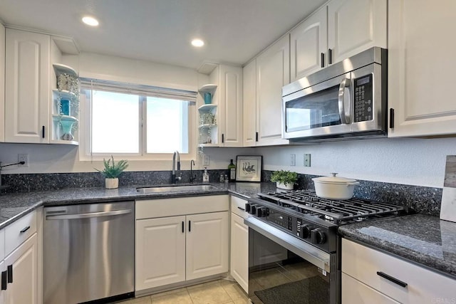 kitchen featuring sink, light tile patterned floors, white cabinetry, stainless steel appliances, and dark stone counters