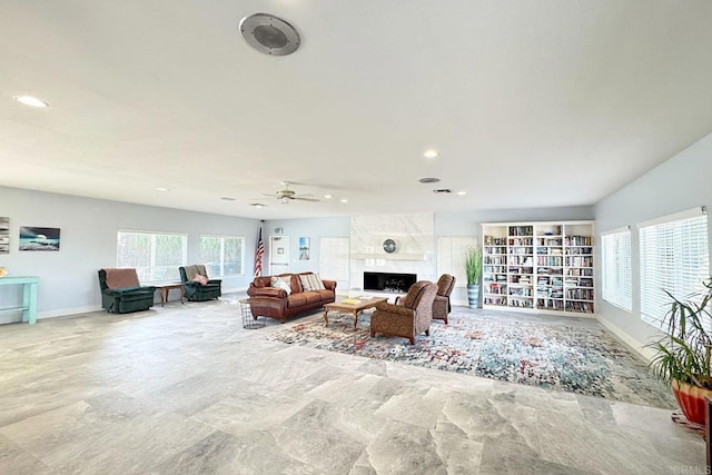 living room with ceiling fan and a high end fireplace