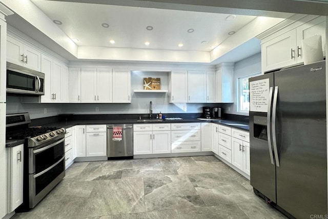 kitchen featuring stainless steel appliances, sink, white cabinets, and a tray ceiling