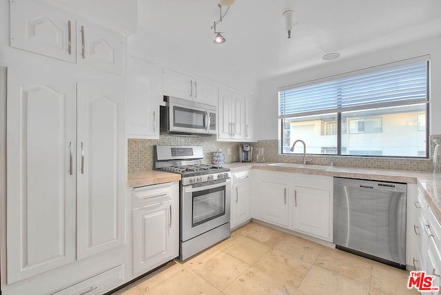 kitchen with stainless steel appliances, tasteful backsplash, sink, and white cabinets