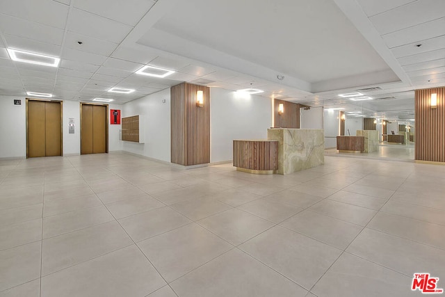 interior space featuring light tile patterned floors, a paneled ceiling, and elevator