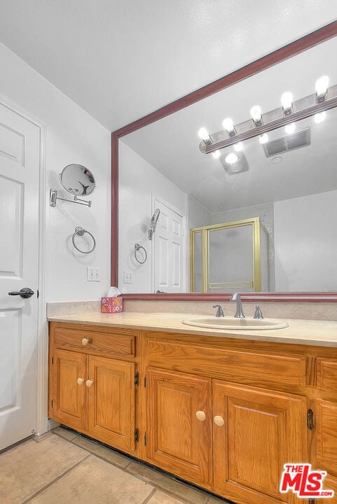 bathroom featuring vanity, tile patterned flooring, and a shower with door