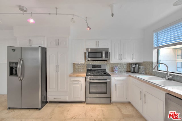 kitchen featuring appliances with stainless steel finishes, sink, white cabinets, and decorative backsplash