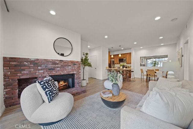 living room with a brick fireplace and light hardwood / wood-style flooring