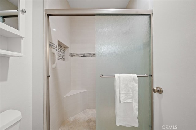 bathroom featuring toilet and a shower with shower door