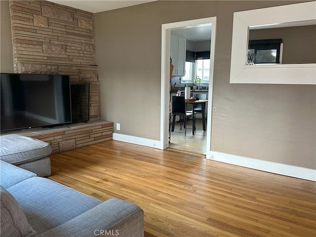 living room with a stone fireplace, sink, and light wood-type flooring