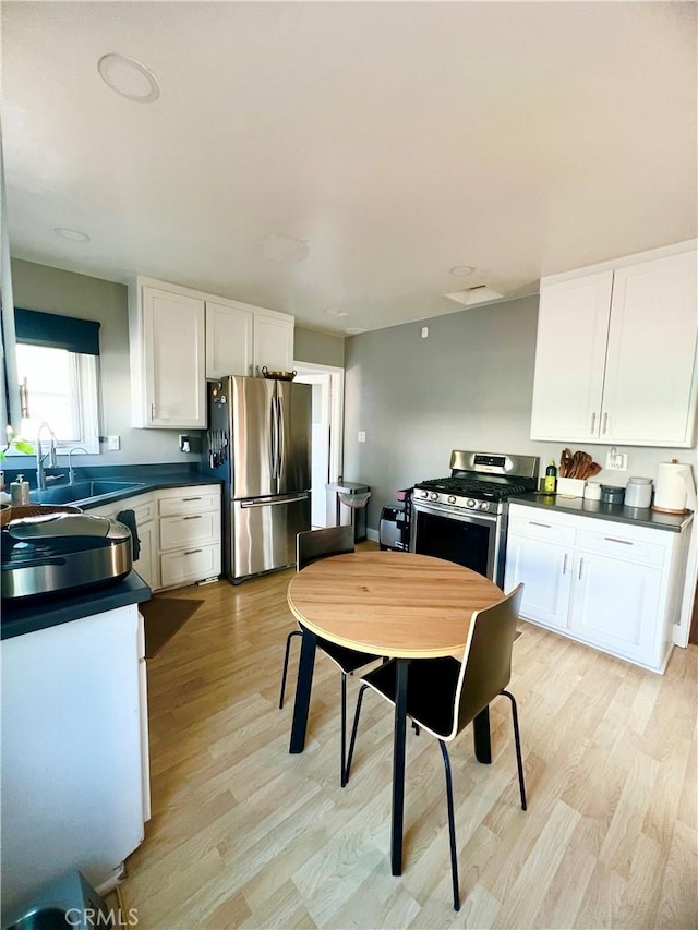 kitchen with stainless steel appliances, sink, light hardwood / wood-style flooring, and white cabinets