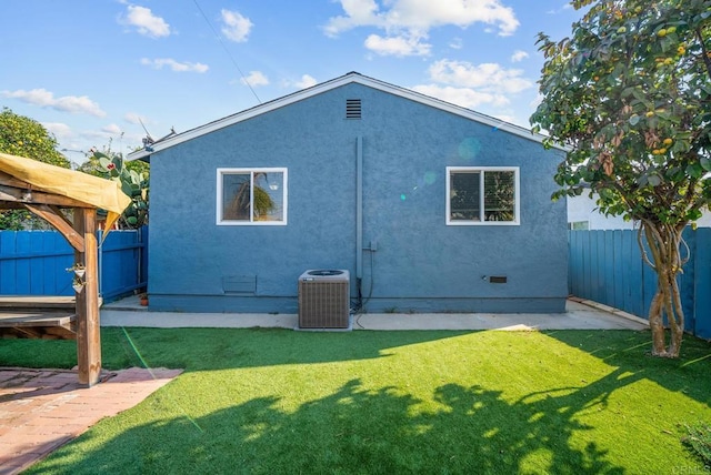 back of house with central AC unit and a lawn