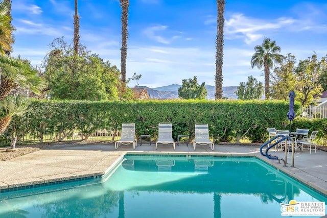 view of swimming pool with a mountain view and a patio area