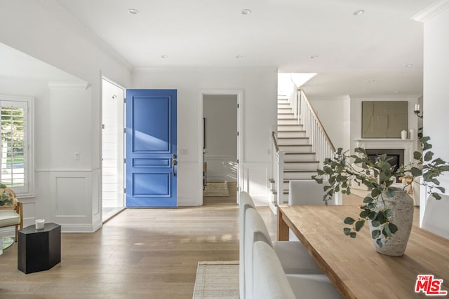 entryway with crown molding and light hardwood / wood-style flooring