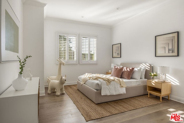 bedroom featuring ornamental molding and light wood-type flooring