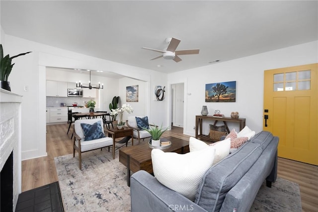 living room featuring ceiling fan with notable chandelier and light hardwood / wood-style floors