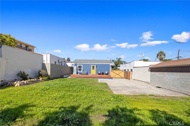 rear view of property with a wooden deck, a yard, and a patio area