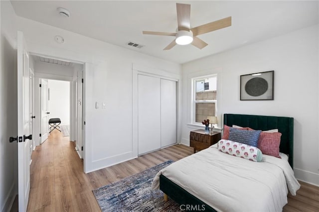 bedroom with light hardwood / wood-style flooring, ceiling fan, and a closet