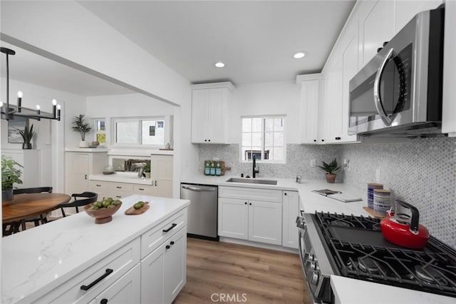 kitchen featuring appliances with stainless steel finishes, sink, hanging light fixtures, and white cabinets