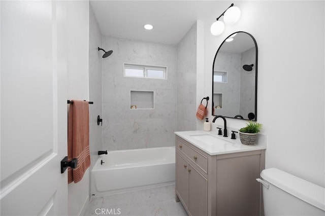 full bathroom with tiled shower / bath, vanity, and toilet