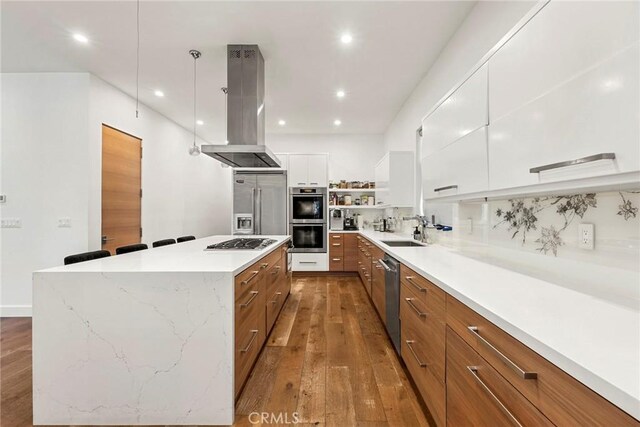 kitchen featuring sink, white cabinetry, island range hood, a kitchen island, and stainless steel appliances