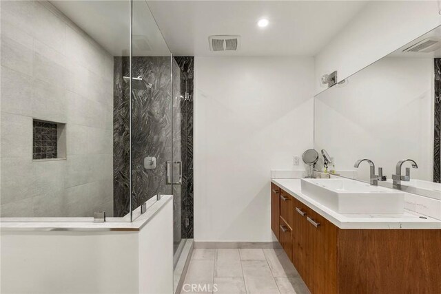 bathroom with tiled shower, vanity, and tile patterned flooring