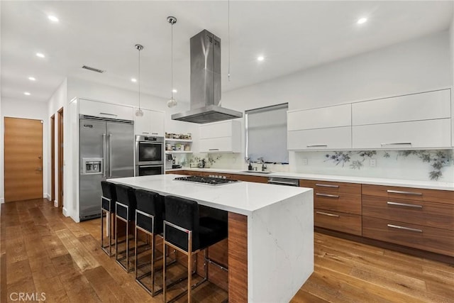 kitchen featuring white cabinetry, island exhaust hood, appliances with stainless steel finishes, and a center island