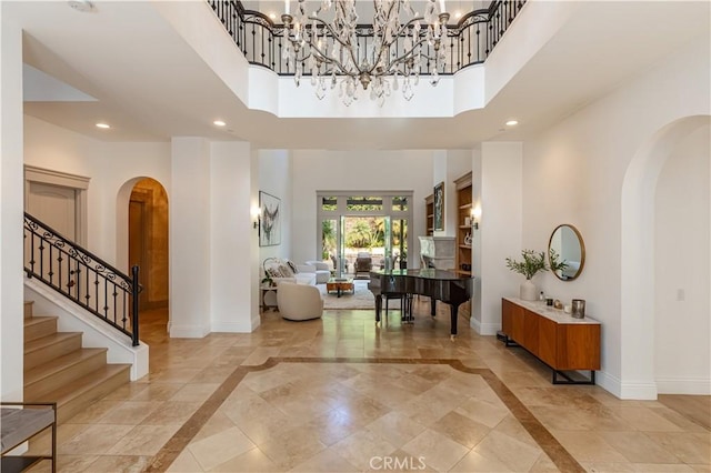 entryway featuring a towering ceiling, baseboards, arched walkways, and recessed lighting