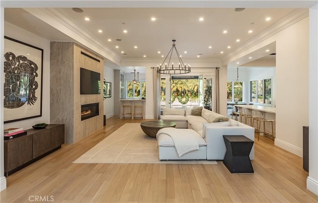 living area with a notable chandelier, a fireplace, recessed lighting, light wood-style floors, and baseboards