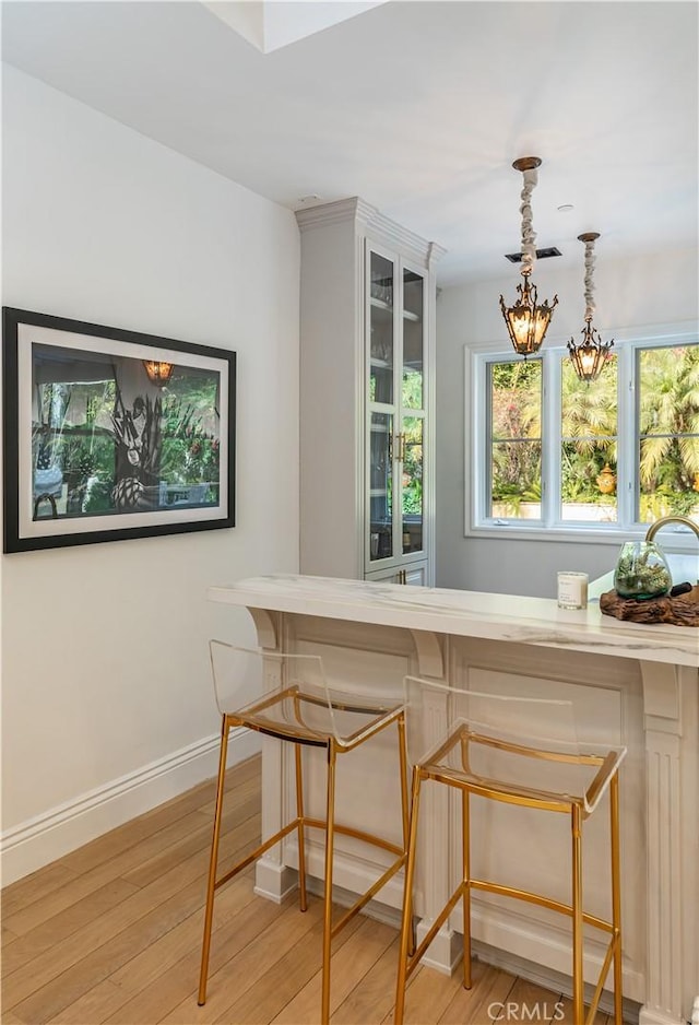 dining room featuring light wood-style flooring, visible vents, baseboards, and a chandelier