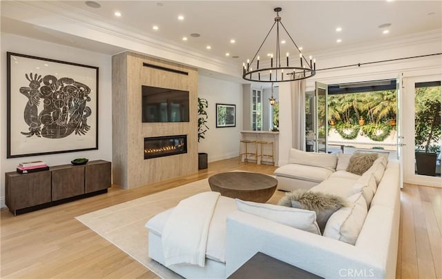 living area featuring a large fireplace, crown molding, recessed lighting, and light wood-style floors