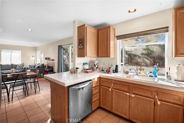 kitchen with light tile patterned flooring, tile countertops, sink, stainless steel dishwasher, and kitchen peninsula