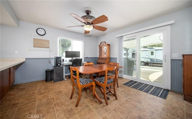 dining space featuring plenty of natural light, ceiling fan, and wood walls