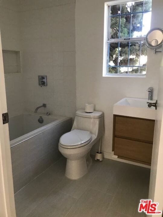 full bathroom featuring tiled shower / bath, tile patterned floors, toilet, and vanity