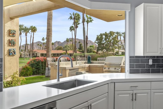 kitchen featuring a mountain view, sink, decorative backsplash, and white cabinets