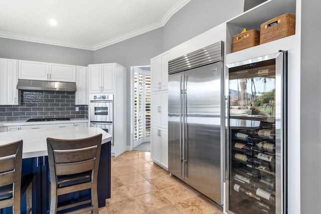 kitchen with stainless steel appliances, white cabinets, wine cooler, and a kitchen bar