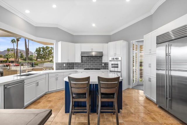 kitchen featuring sink, a breakfast bar area, white cabinetry, appliances with stainless steel finishes, and backsplash