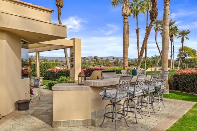 view of patio featuring exterior bar, an outdoor kitchen, and a mountain view