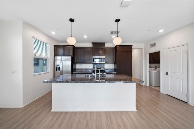 kitchen featuring dark brown cabinetry, sink, appliances with stainless steel finishes, pendant lighting, and a kitchen island with sink