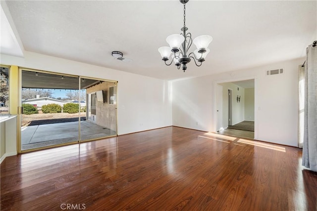 empty room with an inviting chandelier and wood-type flooring