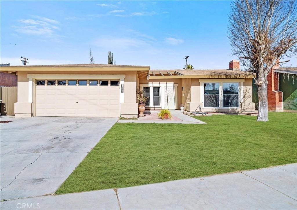 ranch-style home with a garage and a front lawn