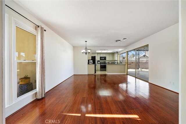 unfurnished living room with a chandelier and hardwood / wood-style floors