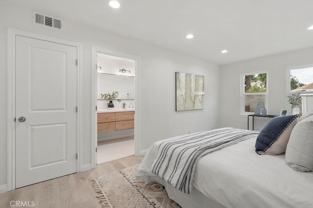 bedroom featuring connected bathroom and light hardwood / wood-style floors