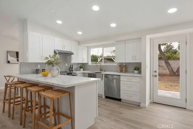 kitchen with white cabinetry, decorative backsplash, appliances with stainless steel finishes, and light stone counters