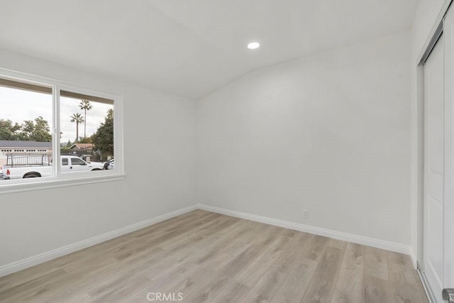 spare room with vaulted ceiling and light hardwood / wood-style floors