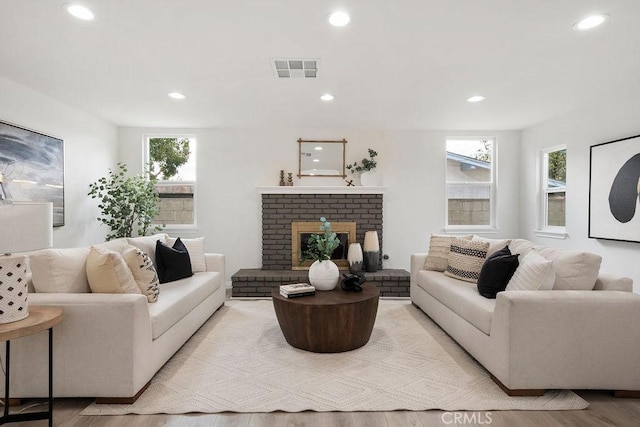 living room with light hardwood / wood-style floors and a brick fireplace