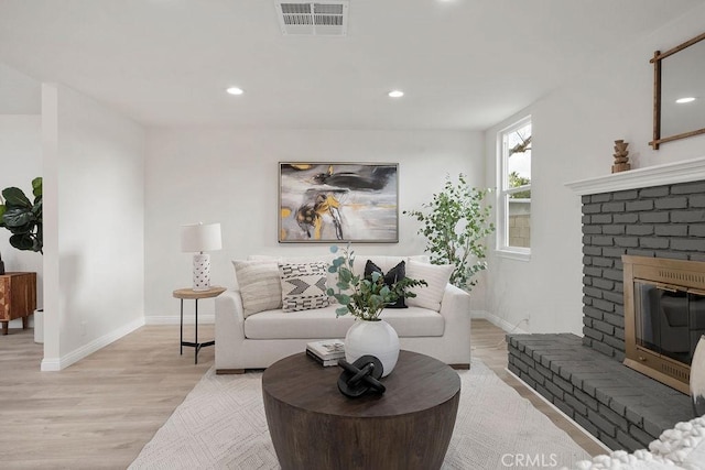 living room with a fireplace and light wood-type flooring