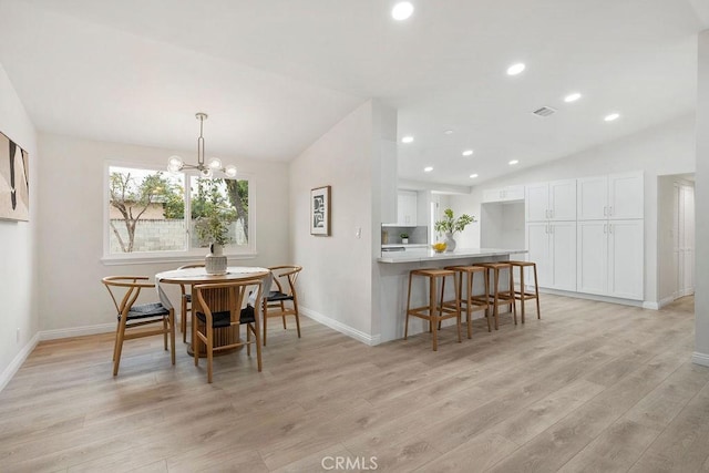 dining area featuring vaulted ceiling, a chandelier, and light wood-type flooring