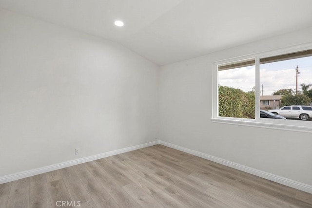 empty room with light hardwood / wood-style flooring and vaulted ceiling