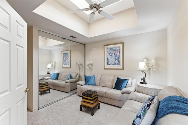 living room with ceiling fan and a raised ceiling