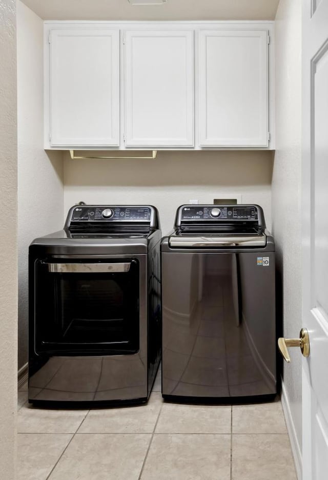 washroom with cabinets, separate washer and dryer, and light tile patterned floors