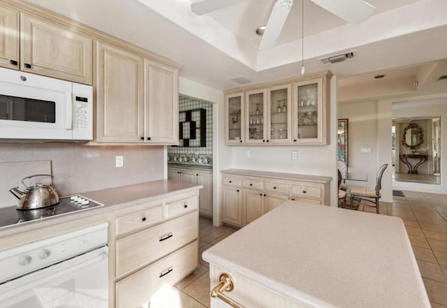 kitchen featuring white appliances, ceiling fan, backsplash, light tile patterned flooring, and a raised ceiling